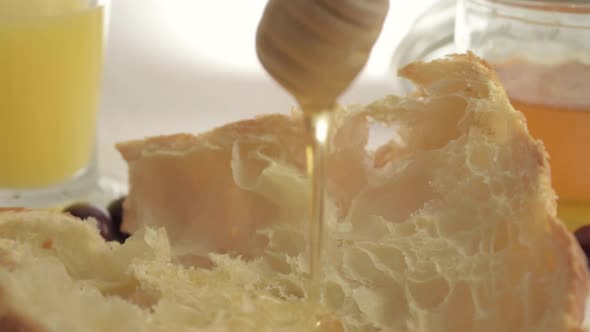 Drizzling honey on fresh baked croissant close up shot alt