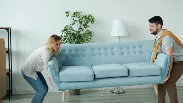 Young Couple Bringing New Sofa To Apartment Then Sitting Relaxing Enjoying Rest During Relocation alt
