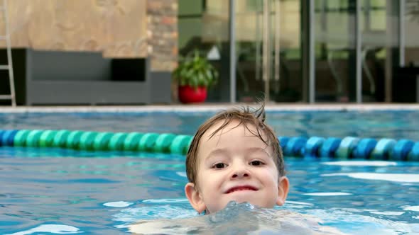 Cheerful Little Boy in Goggles Bathing in the Pool alt
