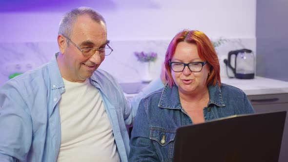 Happy Old Middle Aged Couple Using Laptop Talking Together Doing Online Shopping Senior Mature alt
