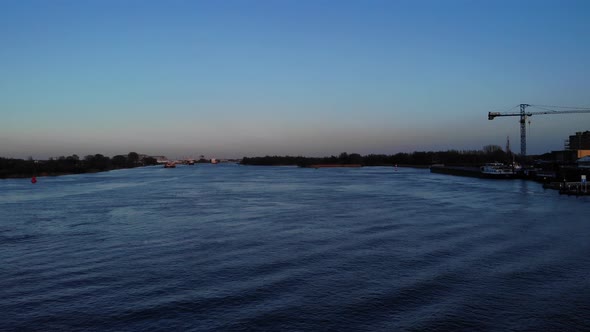 Industrial Seaport With Crane On Calm Water With Distant Ships Sailing Oude Maas River In South Holl alt