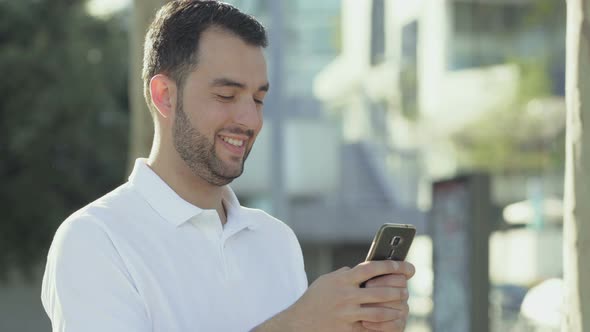 Smiling Bearded Man with Smartphone Posing During Sunny Day alt