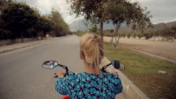 Woman In Face Mask  Riding On Scooter On Lockdown Coronavirus. Discovering New Route. alt