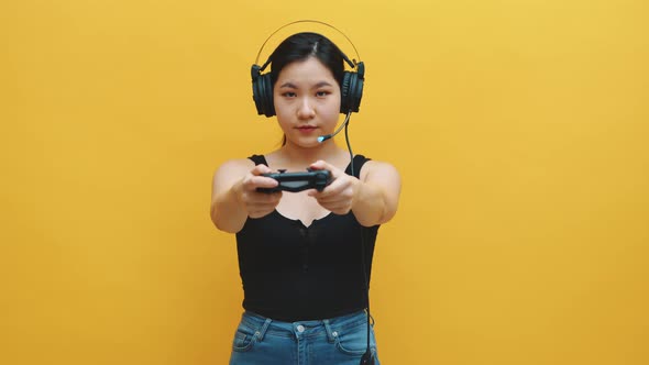 Focused Young Asian Woman with Headset and Joystic Controller Playing Video Games. Isolated on alt