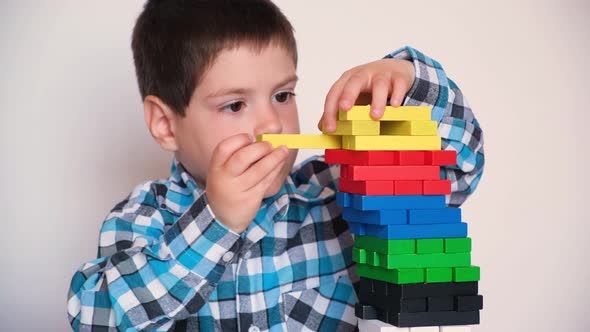 A 4Yearold Boy Plays a Board Game of Jenga Pulling Multicolored Blocks Out of the Tower alt