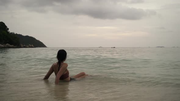 Asian Women Sitting On The Beach And Looking Toward The Sky At Sunset 2