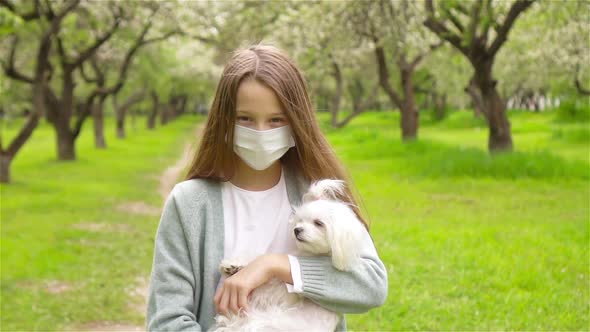 Little Girl with Dog Wearing Protective Medical Mask for Prevent Virus Outdoors in the Park