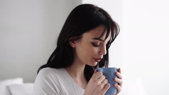 Pregnant Young Woman Drinking Tea And Sitting On Bed At Home alt