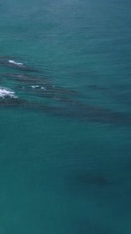 Vertical Aerial Shot From Ocean Across Rocky Land and Back to Water