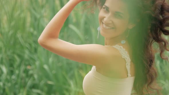 Happy mixed race woman dancing outdoors on green nature background, slow motion
