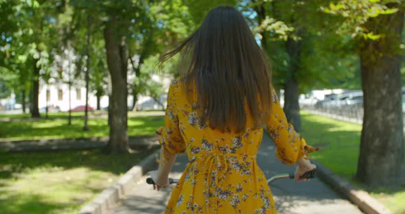 Cyclist Woman In Park In Dress. Sport And Recreation. Cycling Woman In City Park On Bicycle. alt
