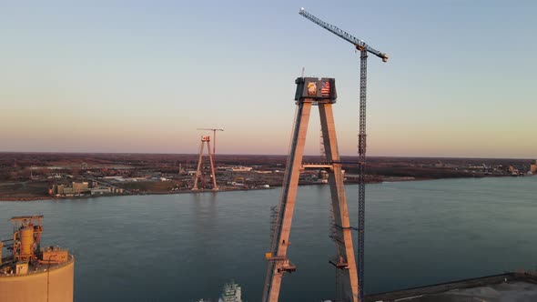 Forwarding aerial shot of the Gordie Howe Bridge under construction, Suspension tower with crane, De alt