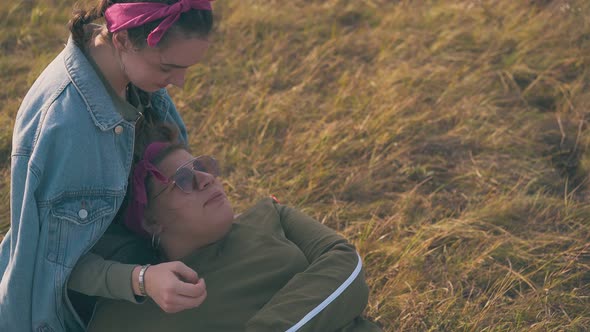 Young Women Spend Nice Time on Dry Grass By Camp at Sunset alt
