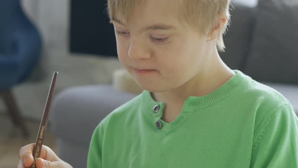 Closeup of Boy with Down Syndrome Drawing at Home