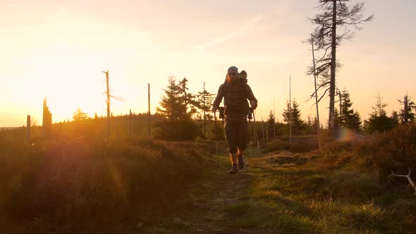 male hiker hiking with a backpack on a trail during beautiful sunset,