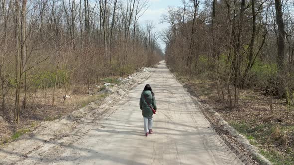 Girl Walking in the Spring Forest. Copter Watches the Girl From Behind