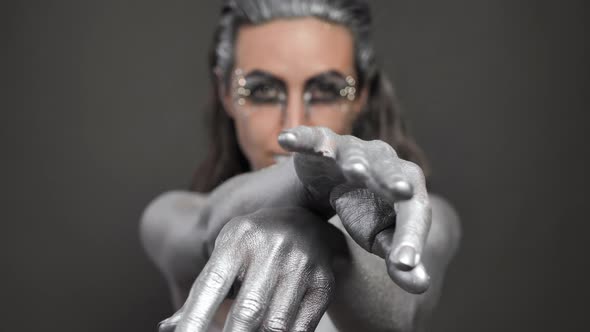 Closeup of a Beautiful Woman's Hands with Silver Paint on Her Skin and Hair