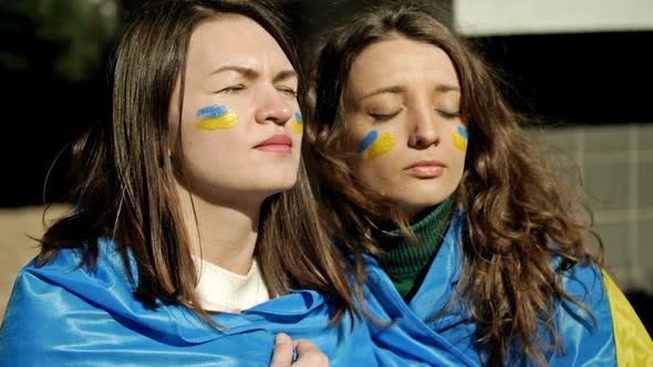 Women with the Flag of Ukraine on Their Shoulders Looking Into the Distance with Excitement and Hope alt