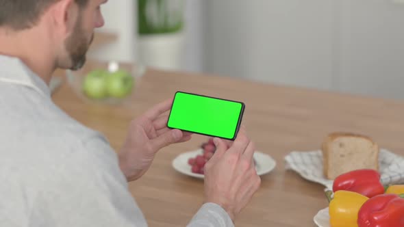 Rear View of Young Man Looking at Smartphone with Chroma Key Screen alt