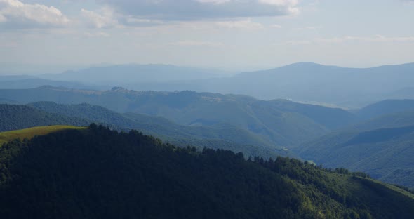 High Mountains Are Covered With Forests. Clouds Float Over The Mountains