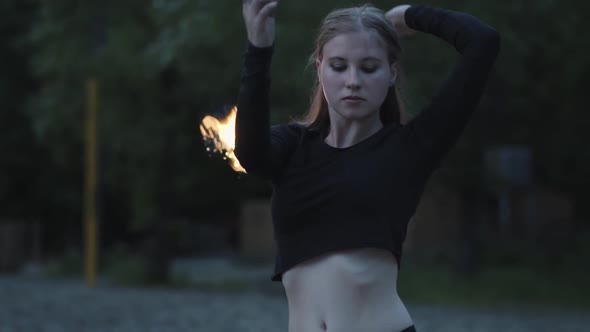 Portrait of Blond Confident Woman Performing a Show with Flame Standing in the Forest or Park alt