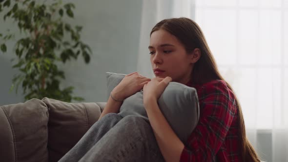 Pensive Lady Cries Hugging Pillow on Sofa in Living Room alt