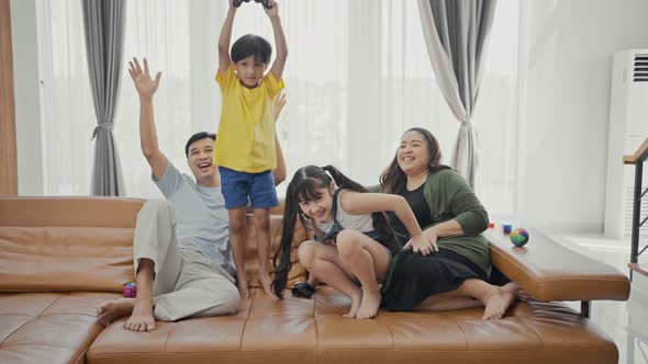 Happy family adult parents with cute kids relax on sofa playing video game having fun with together. alt