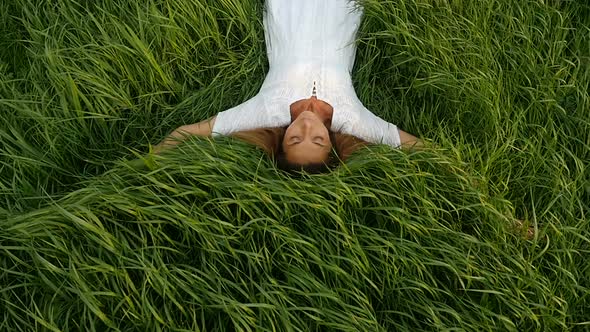 Young Cute Woman Dreams on the Nature. Beautiful Young Woman Lying on the Field.