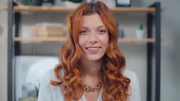 Young Caucasian Woman Looking at Camera Cutely Blinking and Smiling alt
