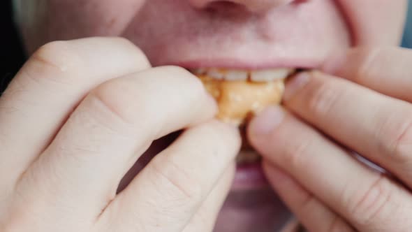 A Hungry Man Eagerly Eats a Hamburger Only His Mouth is Visible in the Frame alt