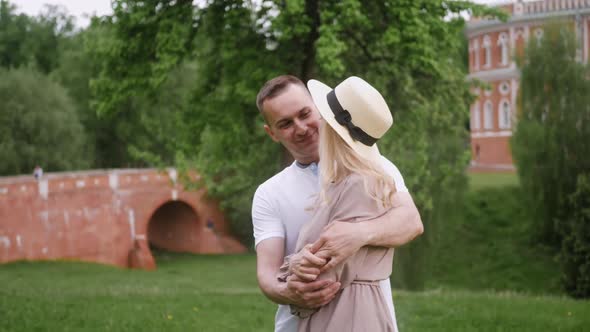 Man with a Woman Blonde in a Dress Dance on a Green Field in Nature in Summer