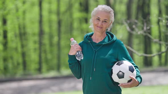 Medium Shot of Fit Charming Confident Senior Sportswoman Smiling Looking at Camera Standing Outdoors alt
