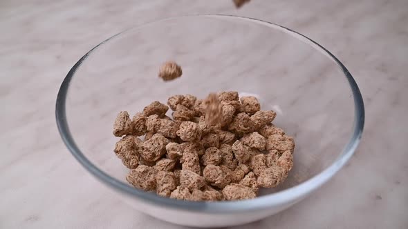 Wheat bran slowly falls into glass bowl. Crunchy Breakfast cereals, slow motion alt