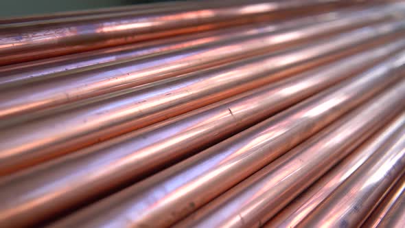 Metal, copper pipes stack with shiny reflections at warehouse.