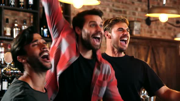 Excited friends watching television while having beer alt