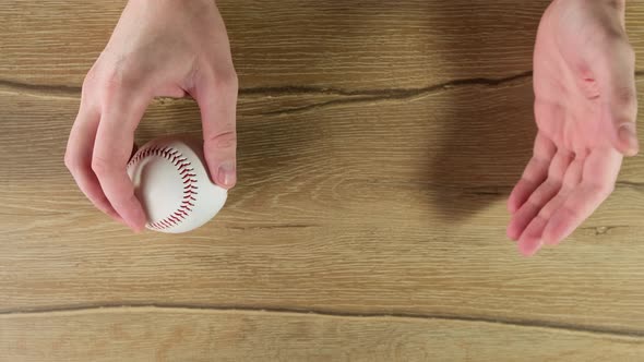 Throwing a Baseball Up on Wooden Black Background. Close Up.
