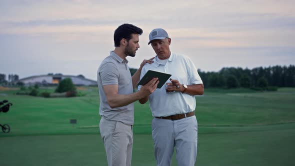 Modern Sportsmen Holding Tablet Browsing Web on Golf Field alt