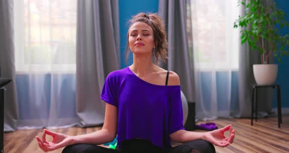 Portrait of Beautiful Young Woman Dressed in Fitness Clothes Meditates While Sitting in Lotus alt