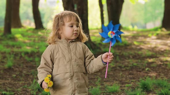 Portrait of Serious Cute Light Hair Little Girl with Windmill Toy