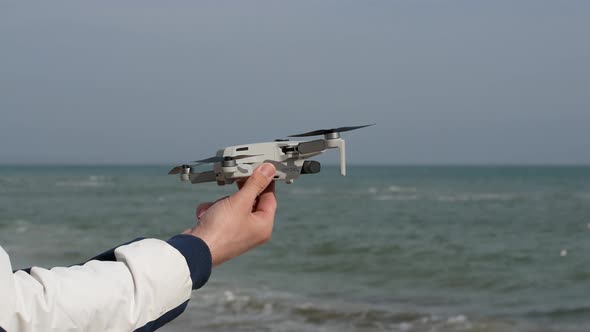 The drone lands on a man's hand - against the background of the blue sea. Close-up alt