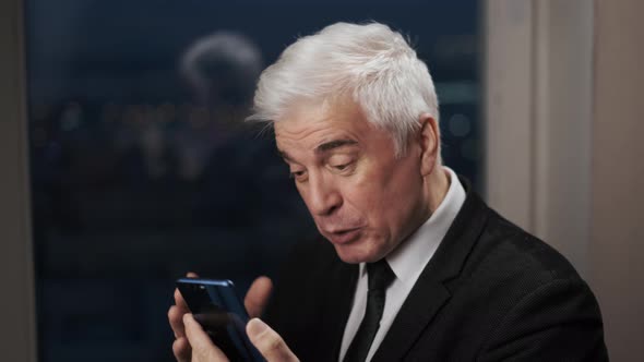 Old Elderly Senior Businessman in Blazer Has Distant Smartphone Conference Call