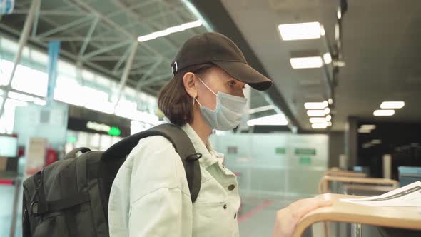 A Woman in a Mask and with a Backpack Behind Her Back Near the Checkin Desk to Board the Aircraft alt
