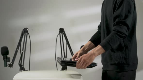 a man putting down and opening a laptop with a podcast setup background