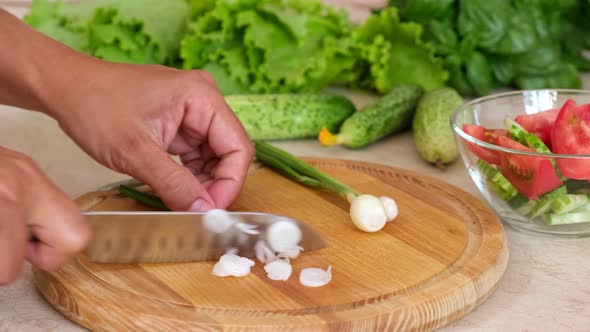 Woman hands cut fresh green onions to make salad, homemade food.