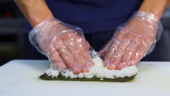 Chef in gloves is preparing sushi.  alt