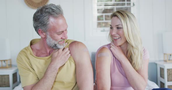 Happy caucasian mature couple showing plaster on arm where they were vaccinated against coronavirus alt