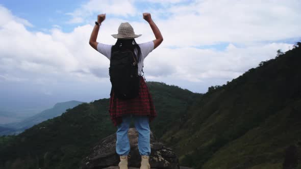 Backpacking female hiker stands on top of the mountain and enjoying the view. alt