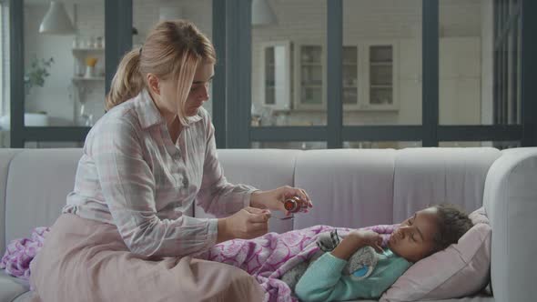 Caring Mother Giving Cough Syrup To Sick Child alt