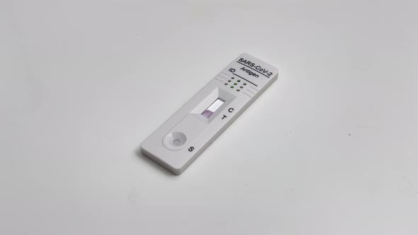 Performing COVID-19 antigen flow test. Flow to a positive result on the test pad. Wide framing. Quic alt