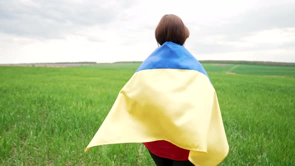 Unrecognizable Ukrainian Woman Walking with National Flag in Green Field alt